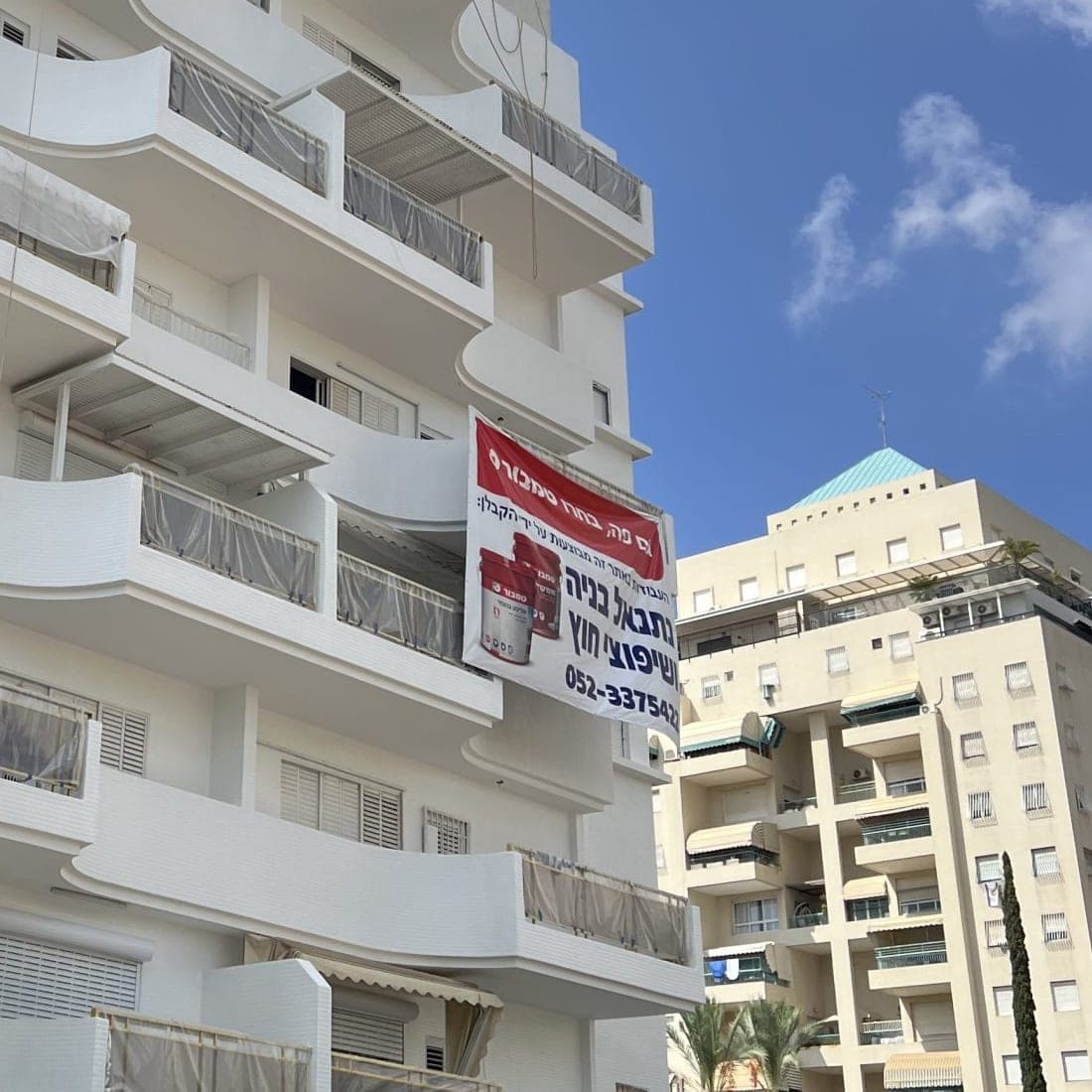 השלט של נתנאל בנייה ושיפוצי חוץ על בניין בזמן העבודות